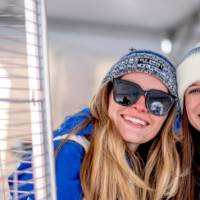 Two alums smile next to a heater